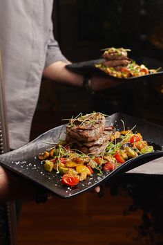 a person holding two plates with food on them