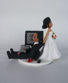 a bride and groom figurine sitting next to each other on a white surface