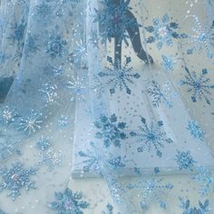 blue snowflakes on white sheer fabric with silver sequins in the center