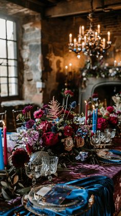 the table is set with blue and red cloths, silverware, candles, and flowers