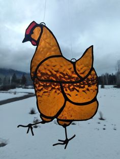 a stained glass chicken hanging in the snow