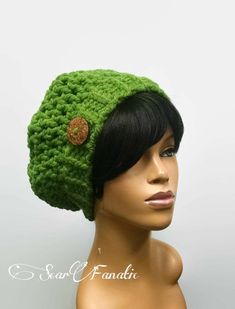 a mannequin head wearing a green crochet hat with a brown button