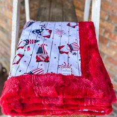 a red and white blanket sitting on top of a chair next to a brick wall