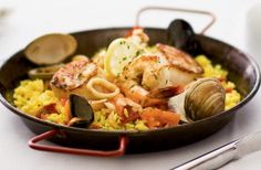 a pan filled with seafood and rice on top of a table