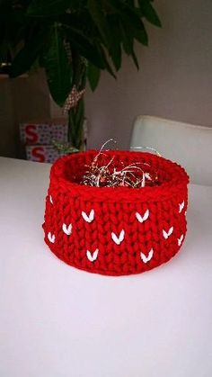 a red knitted bowl sitting on top of a white table