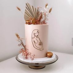 a pink cake with gold decorations and feathers on it's top tier, sitting on a white table