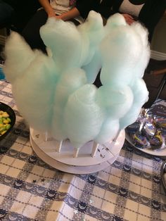 there are some cotton candy on top of a table with people sitting around the table in the background