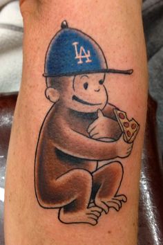 a monkey with a baseball cap on his head holding a slice of pizza and eating it