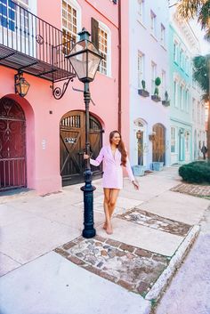 a woman in a pink shirt is standing by a street light and some colorful buildings