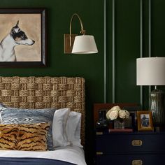 a bedroom with green walls and pictures on the wall above the bed, along with a tiger print pillow