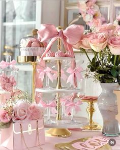 a table topped with lots of pink flowers and vases filled with cake on top of it