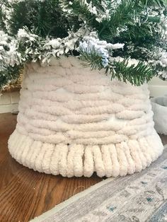 a potted plant is covered with white yarn and pine needles, sitting on a wooden floor