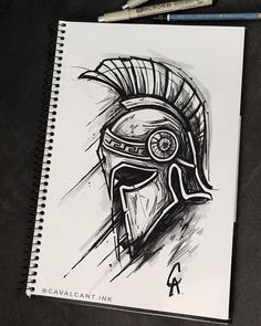 a drawing of a spartan helmet on top of a notepad next to some markers