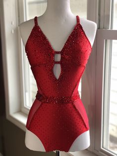 a red leotard with sequins on it sitting in front of a window