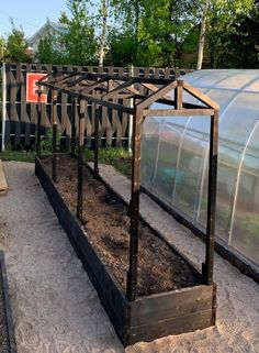 there is a small greenhouse in the middle of some dirt and sand on the ground