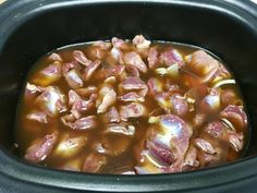 the food is being cooked in the crockpot with meat and onions on top