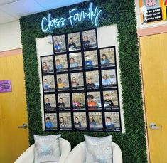 an office cubicle decorated with green ivy and photos on the wall above two white couches