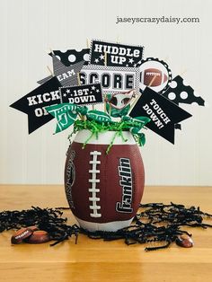 a football centerpiece with black and white decorations in it on top of a wooden table