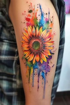 a colorful sunflower tattoo on the right arm and shoulder, with paint splatters all over it