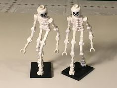 two white plastic skeleton figurines standing on black bases