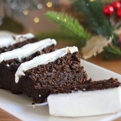 slices of chocolate cake with white frosting on a plate next to a christmas tree