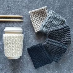 there are knitted items on the floor next to a coffee cup and chopsticks