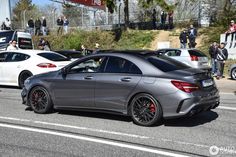 the mercedes cla is driving down the road in front of other cars and people