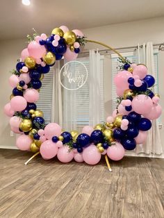 a balloon arch with pink, blue and gold balloons in the shape of a wreath