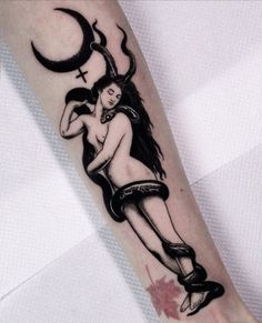 a tattoo on the arm of a woman with a cross and moon in her hand