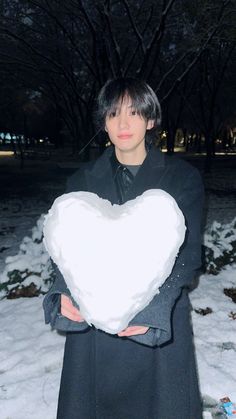 a person holding a heart shaped pillow in the snow