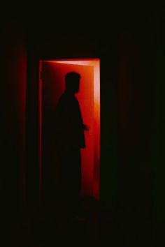 a man standing in an open doorway at night