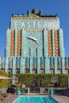 an outdoor swimming pool in front of a large building with a clock on it's side