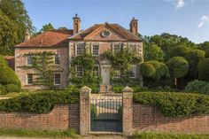 a large brick house with an iron gate and ivy covered hedges on the front yard