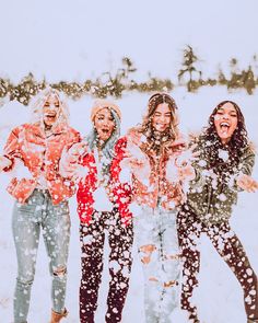 four girls are standing in the snow and laughing