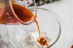 the ingredients are being poured into a glass bowl