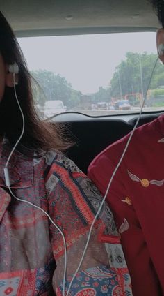 two people sitting in the back seat of a car with headphones attached to their ears