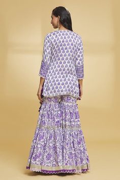 White and purple three fourth sleeves A-line kurta with all over bud bloom garden print and gota lace, sequin highlights. Paired with a matching fleur print and gota lace, thread tassel embellished tiered gharara and dupatta with gota weave border detailing. - Aza Fashions Designer Long Sleeve Purple Palazzo Set, Long Sleeve Purple Palazzo Set For Diwali, Long Sleeve Purple Sharara For Eid, Long Sleeve Purple Palazzo Set For Wedding, Bohemian Purple Sets, Bohemian Purple Sets With Dupatta, Bohemian Purple Set With Dupatta, Bohemian Purple Wedding Sets, Purple Bohemian Wedding Sets