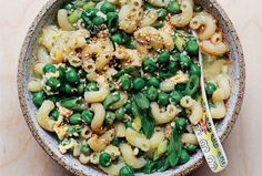 a bowl filled with pasta and peas on top of a table