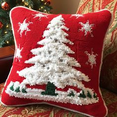 a red christmas pillow with a white tree on it