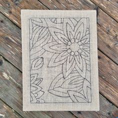 a piece of cloth with an embroidered design on it sitting on a wooden table next to scissors