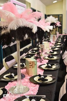 the table is set with black and white plates, silverware, and pink centerpieces