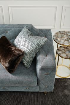 a blue couch with two pillows on top of it next to a table and side tables