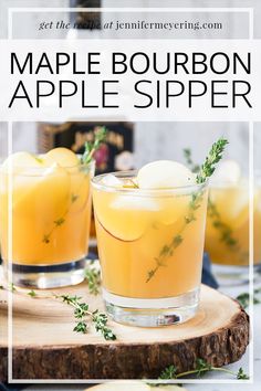 two glasses filled with maple bourbon apple siper on top of a wooden board and surrounded by greenery