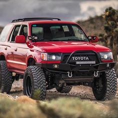 a red truck driving down a dirt road