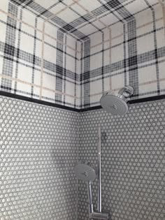 a bathroom with a toilet, shower head and tiled walls in grey and white colors