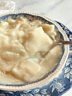 a bowl filled with dumplings on top of a blue and white plate next to a spoon