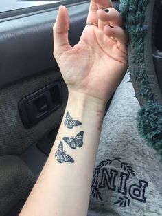 a woman's arm with a butterfly tattoo on her left wrist and the other hand