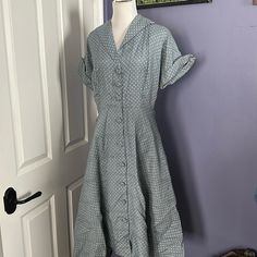 This Grey-Blue Polka Dotted Shirt Dress, With Cuff Sleeves Coming To A Point And Functional Buttons Throughout Skirt And Bodice Is A Perfect Spring Or Summer Piece! It Has A Silky Feel, But Unsure Of Material As The Care Tags/Label Are Not In Garment. One Shoulder Pad Is Missing Easily Replaced One Button Is Securely Attached With A Safety Pin On Inside, And Still Functions This Way. Armpits Have Fading, As Seen In Photos. Dress In First Few Photos Is Shown With Crinoline, Which It Does Not Come 1950s Vintage Dress With Buttons For Daywear, 1950s Collared Daywear Dresses, 1950s Collared Day Dresses, 1950s Style Vintage Dress With Short Sleeves For Daywear, 1950s Style Short Sleeve Dresses For Daywear, 1950s Short Sleeve Vintage Dress For Garden Party, 1950s Style Short Sleeve Day Dresses, Classic Vintage Midi Dress For Daywear, 1950s Style Knee-length Vintage Dress For Daywear