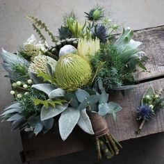 an arrangement of flowers and greenery on a wooden table