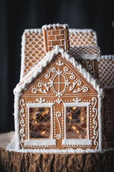 a gingerbread house is decorated with icing and lit up windows for the holiday season